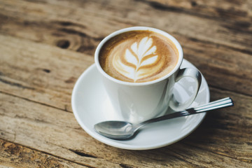 Cup of hot coffee with milk art on the surface placed on the wooden table