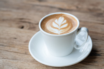 Cup of hot coffee with milk art on the surface placed on the wooden table
