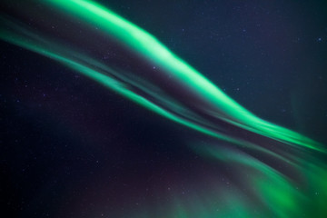 colorful northern light aurora borealis with purple, red, green and blu flames over the sky in iceland in a beach in