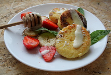 strawberry and cream. Cottage cheese pancakes cottage cheese with strawberry, mint, and banana. Ukrainian traditional food. Ukrainian national kitchen.