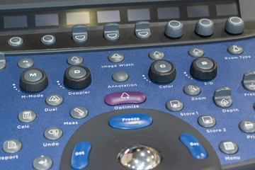 Control panel with trackball. Medical ultrasound diagnostic machine. Buttons, pens, handle, lever. Blue color, lens flare, blur.