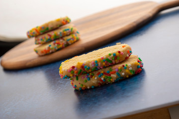Galleta con grageas de colores en estudio con fondo oscuro azul