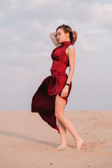 Fototapeta na wymiar Girl in red dress at sunset in the desert