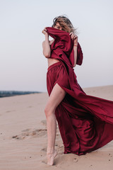 Girl with red cloth in the sunset rays in the desert