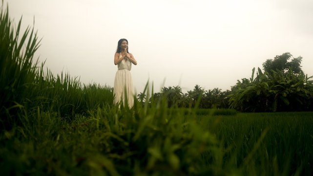 Body And Mind Connection With Nature - Happy And Beautiful Asian Korean Woman Doing Yoga And Meditation Exercise Outdoors At Idyllic Green Rice Field Enjoying Tropical Holidays