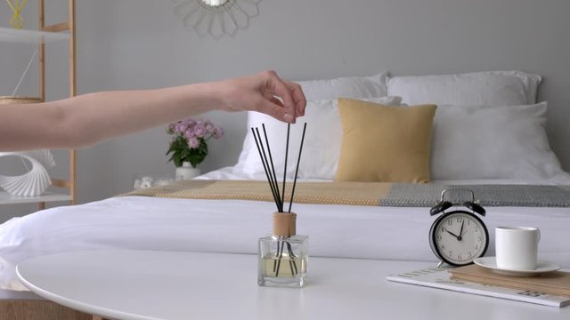 Woman with air reed diffuser on bedside table in room