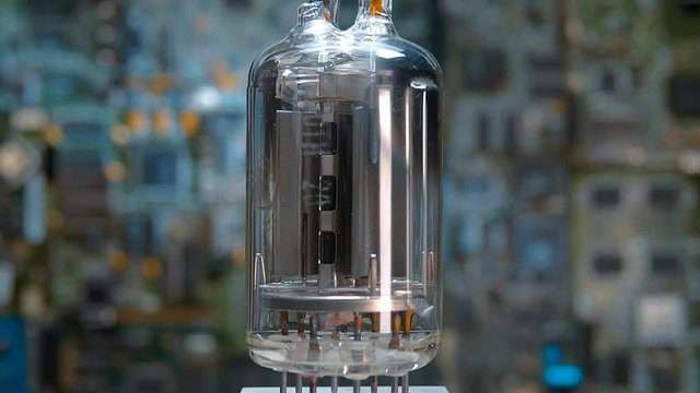 Old vacuum electronic lamp stands on the background of a modern digital electronic board. Macro. Closeup. Shallow depth of field. Rotation