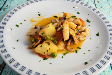 Cuttlefish with peas, potatoes and tomato.