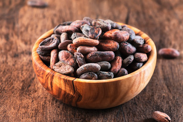 Unpeeled cocoa bean on wooden rustic background, close-up. Copy space