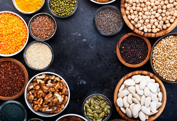 Superfoods, legumes, nuts, seeds and cereals selection in bowls on grey background. Superfood as chia, spirulina, beans, goji berries, quinoa, turmeric, mung bean, buckwheat, lentils, flax seed