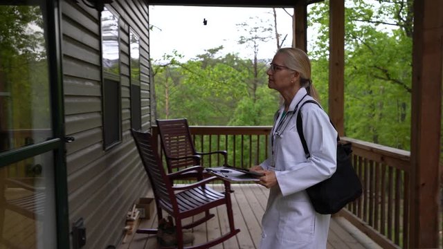 Medium Wide Shot Of Side View Of Nurse Or Doctor Arriving For Home Visit In Rural Area, With Showing ID And Smiling At Door.