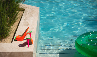 fluorescent high heels next to a pool