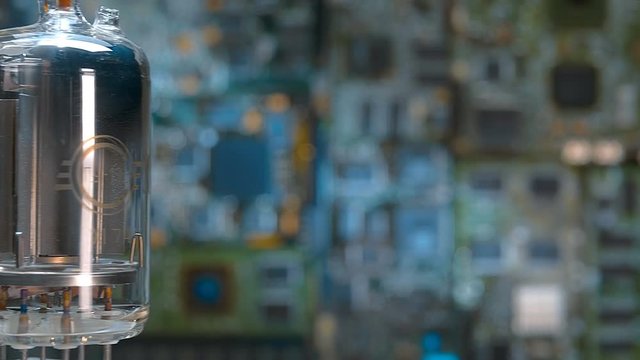 Old vacuum electronic lamp stands on the background of a modern digital electronic board. Macro. Closeup. Dolly shot. Shallow depth of field. Rotation