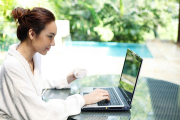 Woman holding a cup of coffee while using laptop