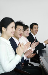 Business people sitting in the board room clapping hands