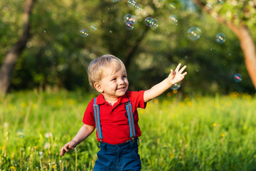 child boy has fun playing in nature with shiny soap bubbles