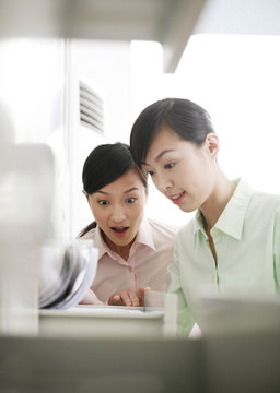 Businesswomen Looking Through File Cabinet