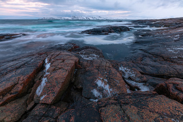 Waves break on the Gulf coast against the backdrop of snow-capped mountains of the Arctic 