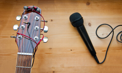 Naklejka premium The neck of a classic six-string guitar with headphones and a black microphone on a yellow board. guitar and accessories. creativity and playing the guitar