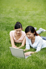 Students lying on field using laptop