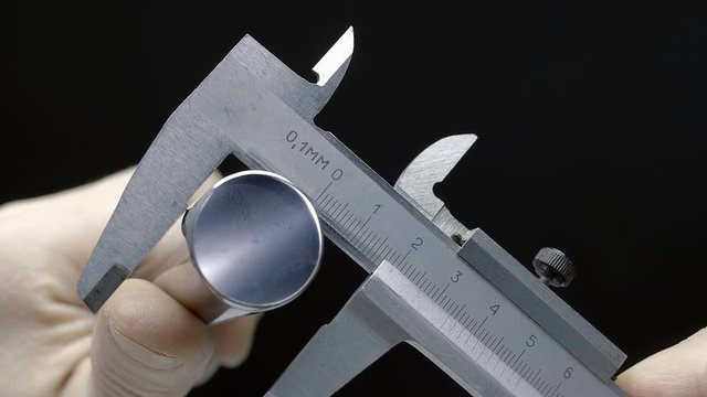 Measurement of the diameter of the pipe (cylindrical metal billet) and the internal diameter of the pipe with a classic metallic caliper. Macro. Closeup