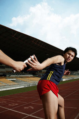 Man passing baton to his teammate in a relay event