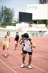 Obraz premium Man passing baton to his teammate in a relay event