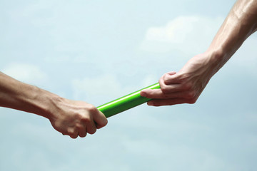 Two men's hands passing the baton in a relay race - obrazy, fototapety, plakaty