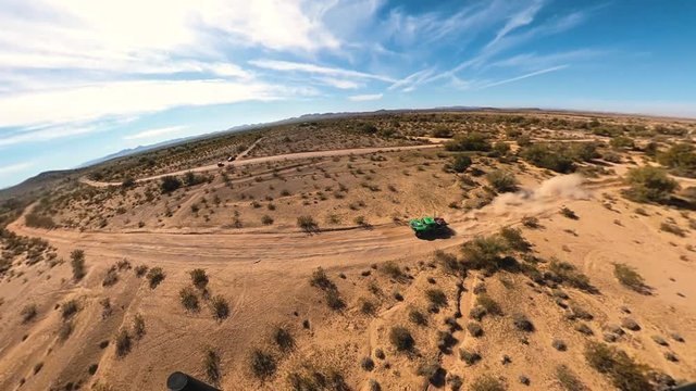 Three sixty view of Green trophy truck racing through desert shot from helicopter