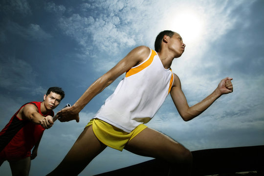 Man passing baton to his teammate in a relay event