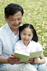 Senior man reading book with girl