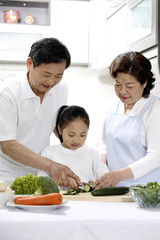 Girl, senior man and woman preparing food in the kitchen