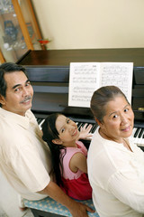 Senior man and woman playing piano with girl