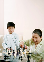 Senior woman and boy playing chess game