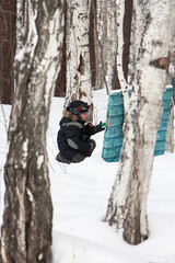 boy playing paintball in the woods