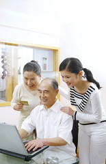 Senior man and woman using laptop for online banking, woman watching