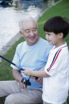 Senior Man Teaching Boy How To Fish