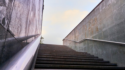 The modern exit from the pedestrian tunnel is empty, up the stairs. Staircase up to the street from the underpass. Stainless steel. color