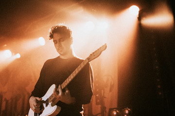 Guitarist playing an electric guitar in a concert - Powered by Adobe