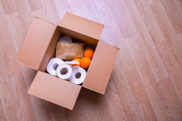 essential products for self-isolation in a box: cereals. toilet paper, fruit, canned food. home delivery. Assistance to population