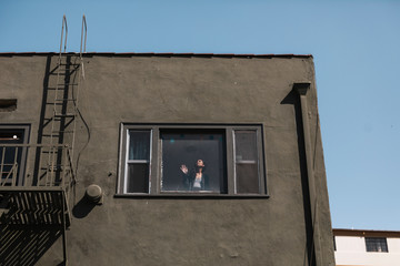 Woman looking out the window of her downtown LA apartment during the covid-19 pandemic
