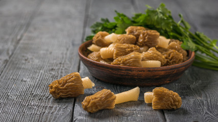 Morels and parsley in a deep bowl on a wooden table.