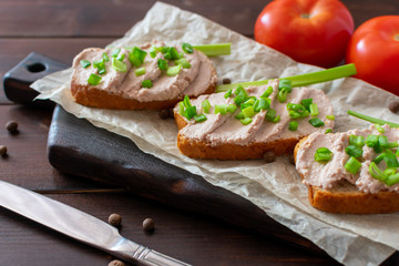 Sandwich with pate with green onion on a wooden background. Sandwich on crumpled paper with herbs.