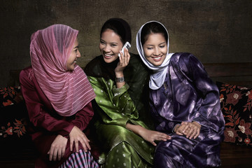 Woman talking on the phone, friends trying to listen to the conversation