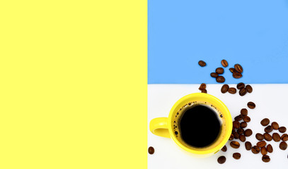 yellow cup of coffee they are natural coffee beans a variety of creative yellow-white, blue backgrounds. The concept of morning coffee, breakfast.Copy space. top view