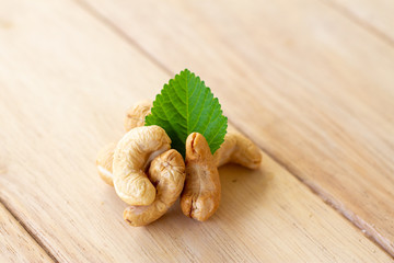 many cashew nut with green leaf on wooden table