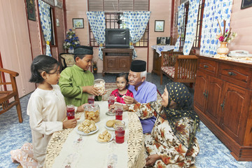 Senior man and woman enjoying cookies with their grandchildren