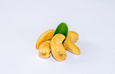 Raw cashew nuts with green leaves isolated on white background. Macro, studio shot