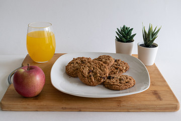 breakfast with oatmeal cookies, apple, accent plants and orange juice