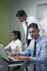 Businesspeople working in conference room under the observation of their superior